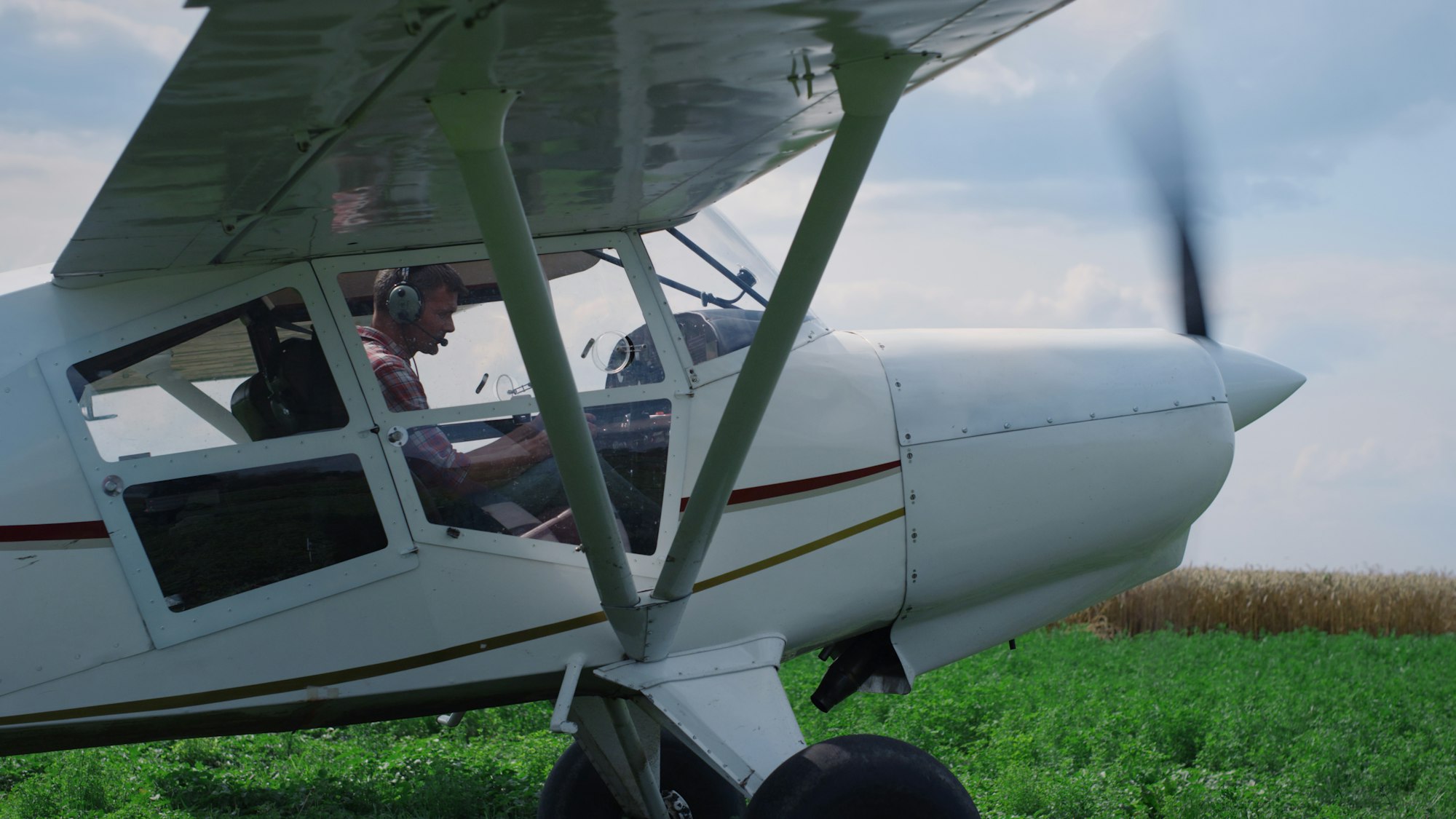 Airplane pilot turning off engine after landing on field. Man parking aircraft.